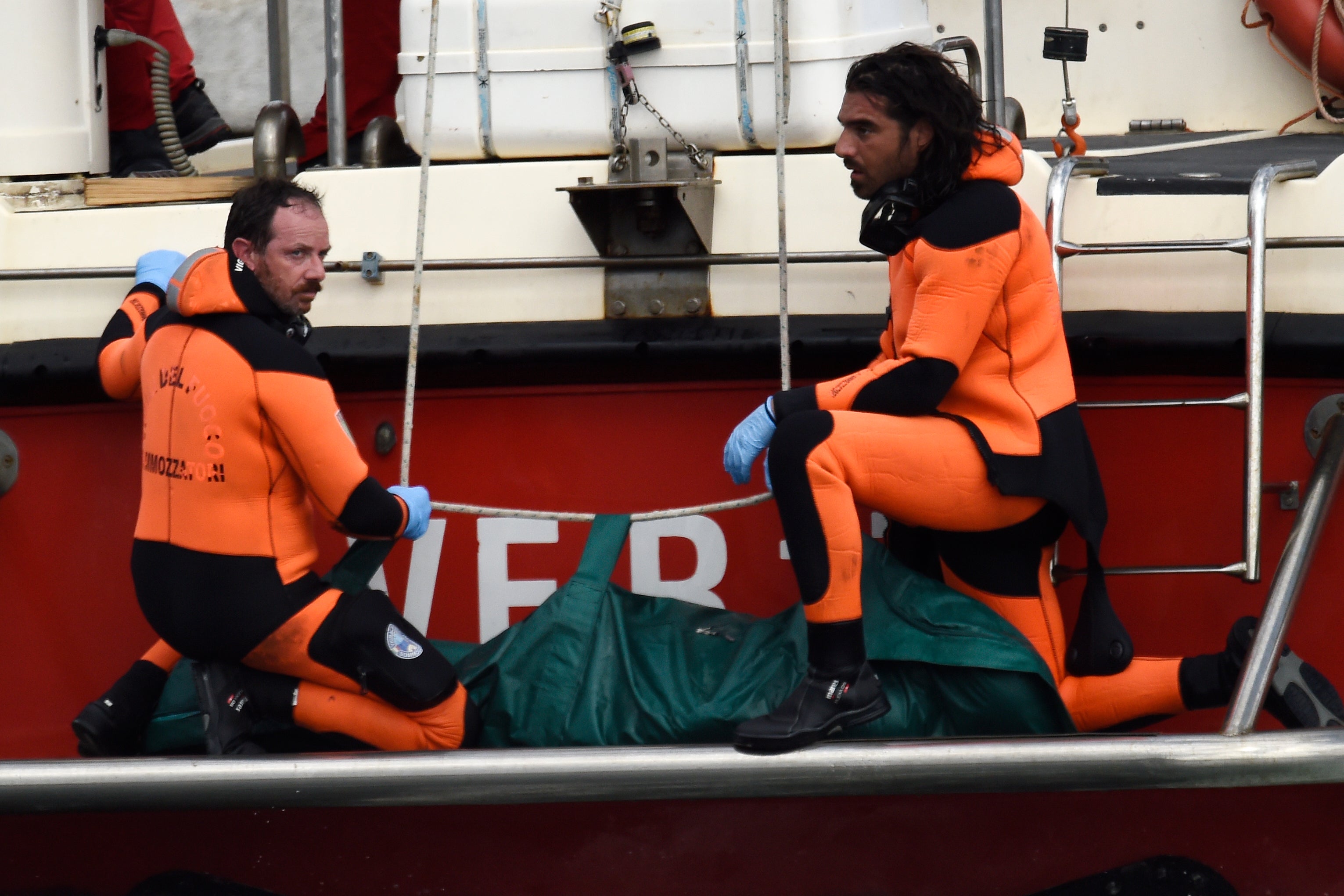 Italian firefighters bring the body of one of the victims of the British-flagged ship Bayesian ashore in a green bag